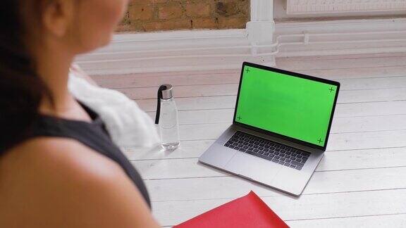 女人在锻炼的时候看着笔记本电脑-色度键绿色屏幕