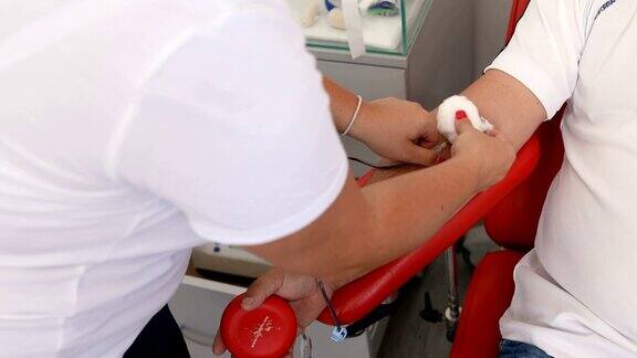 护士从捐赠者的手上取下医用针头好事为身体献血的好处接受输血者的手献血者在医疗诊所献血的特写