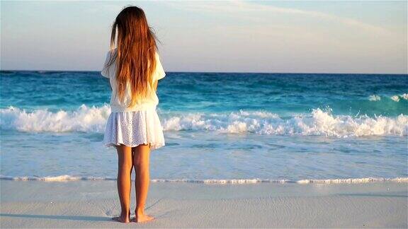 可爱的快乐的小女孩在白色的沙滩上日落