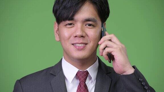 年轻英俊的亚洲商人使用手机