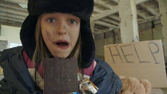 一张叙利亚女孩的肖像肮脏的脸和灰色的眼睛贪婪地吃着巧克力棒
