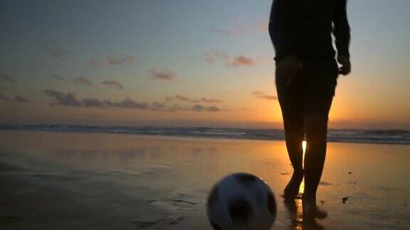 日出时男孩在沙滩上踢足球