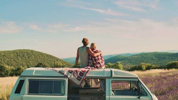 一对夫妇坐在车顶上欣赏风景