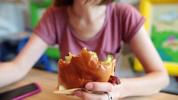 一个饥饿的女孩享受新鲜汉堡的特写