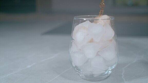 特写:威士忌倒在优雅的玻璃杯中融化的冰块上