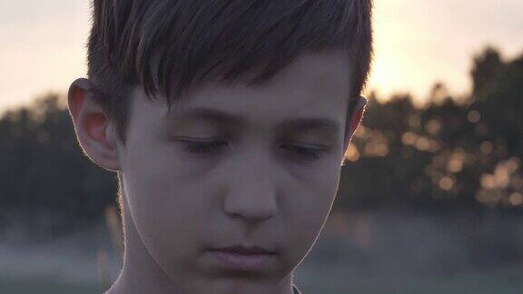 一个悲伤的男孩在麦田里的肖像在日落看近镜头