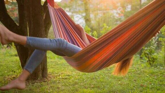 快乐的年轻女子坐在吊床上荡秋千仰望天空