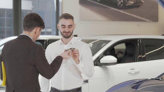 快乐的年轻人从推销员那里收到了新车钥匙