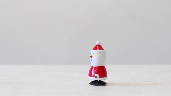 发条塑料圣诞老人玩具走过一个白色的桌子复制空间