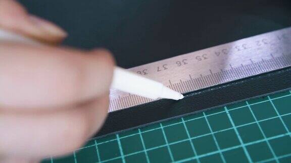 熟练的裁缝用白笔在皮布上画线