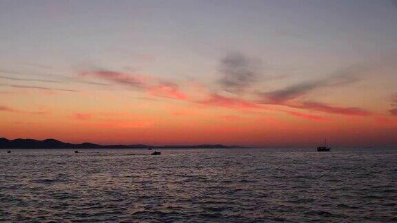 在扎达尔小船在美丽多彩的夏日日落的映衬下移动
