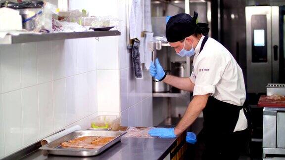 烹饪一位男厨师戴着防护手套和面具正在用鸡排做排骨为顾客准备食物健康食品志愿服务和慈善机构重新开放安全