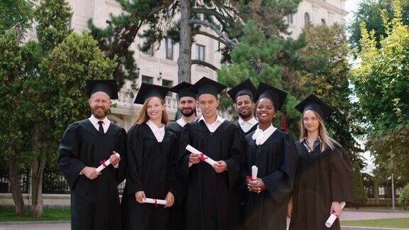 在大学花园的毕业典礼上一群充满魅力和兴奋的学生穿着毕业服戴着毕业帽笑容满面地在镜头前合影留念在ARRIAlexaMini上拍摄