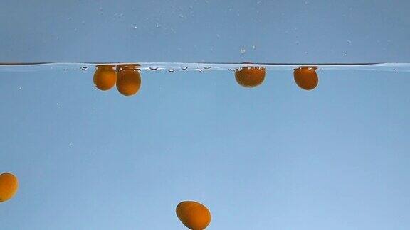 许多橙色的金橘落入水中的慢动作视频
