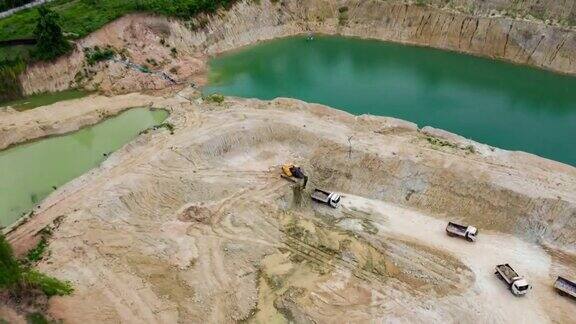 鸟瞰图橙色挖掘机与卡车在采石场工作