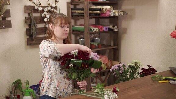 女孩正在为花店准备一束鲜花和绿色植物