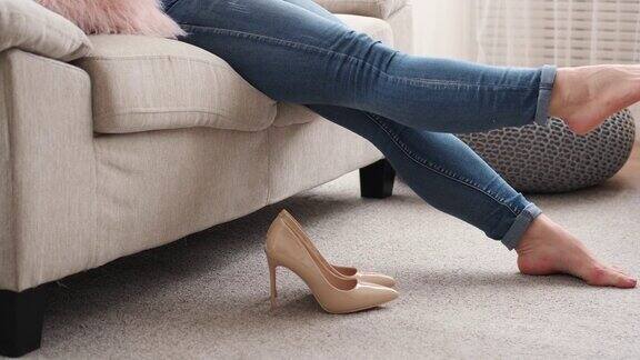 疲惫的女人脱下高跟鞋躺在沙发上休息
