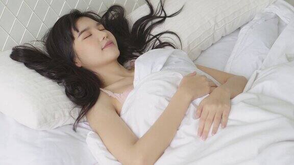美丽的亚洲年轻女子睡在床上枕着枕头舒适和幸福的卧室移动平移相机女孩以放松和休闲为健康生活方式
