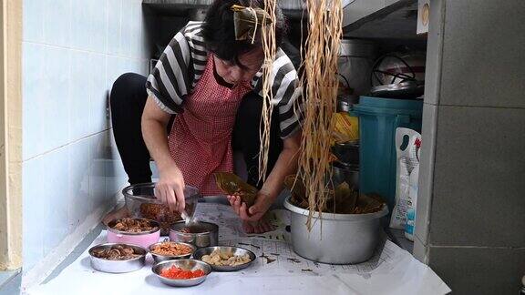 一位年长的亚洲华人妇女在她的厨房里准备粽子把配料包好为端午节做准备