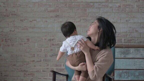 亚洲妈妈把他的儿子抱在怀里笑着把他扔了起来