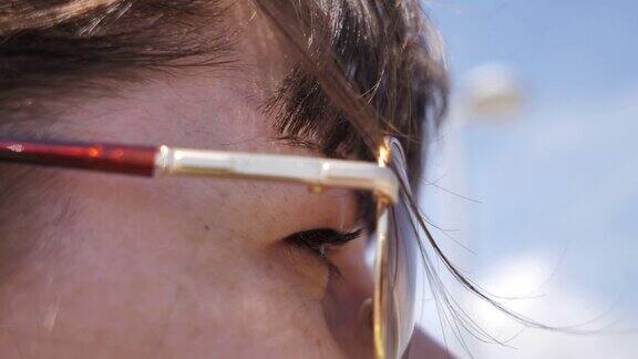 在刮风的天气里戴着眼镜的女孩在思考眼睛的特写