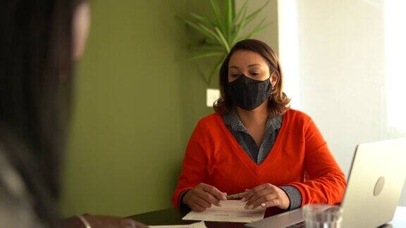成熟的夫妇在家里与房地产经纪人或财务顾问会面戴着防护口罩