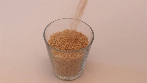 健康的糙米颗粒落入玻璃杯
