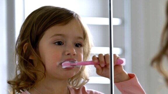小女孩对着镜子认真地刷牙