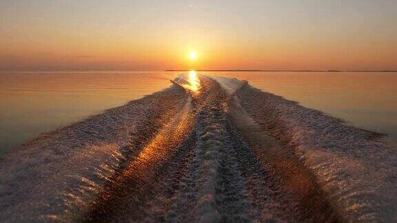 在平静的湖面上从快艇上回头看日落