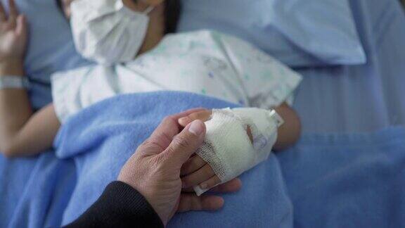 在医院病床上父亲牵着熟睡的儿子的手
