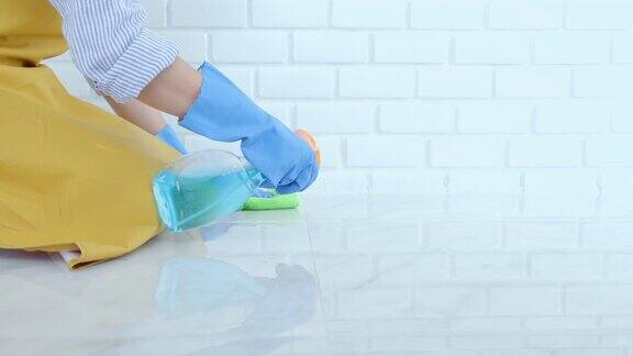 妻子的家务和清洁概念快乐的年轻女子在蓝色橡胶手套用喷雾和抹布擦拭灰尘同时清洁地板在家里