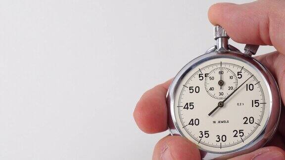机械秒表在人的手中男性手握白底秒表复古模拟秒表的指针在白色背景上隔离了几秒钟按秒表按钮