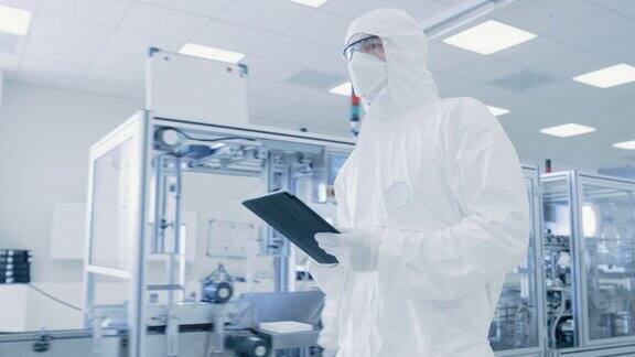 质量控制检查:科学家使用数字平板电脑和穿着防护服走过制造实验室产品制造:制药半导体生物技术