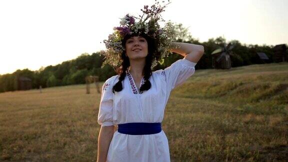 日落时分身着民族服饰、头戴花圈的小女孩走在草地上