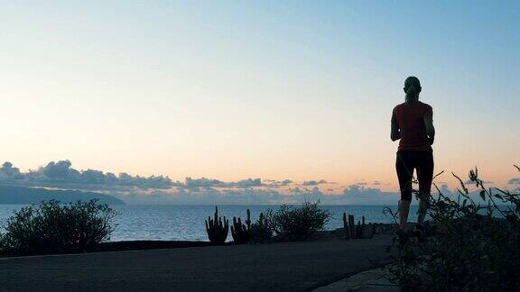 女运动员在日落时沿着海岸跑步