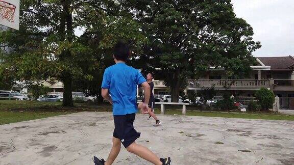 两个亚裔中国男孩放学后在篮球场打篮球和练习篮球