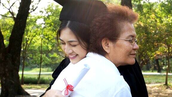 年轻的亚洲女学生戴着毕业帽和毕业礼服在大学女性与毕业概念怀着快乐的心情拥抱母亲的女人