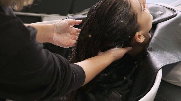 女理发师用护发素按摩头发为年轻女性打理头发