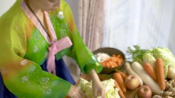 近距离观察穿着韩服的亚洲女性在餐桌上烹饪泡菜和蔬菜