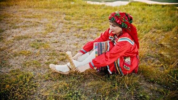 一个穿着俄罗斯民族服装的女人穿着树皮鞋坐在球场上