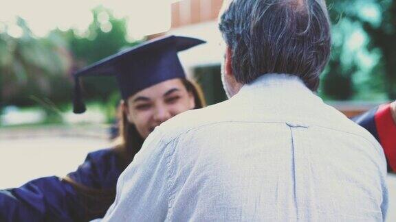 毕业的学生拥抱她的父亲