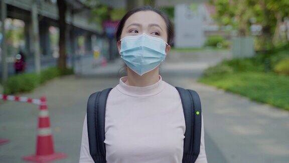 一名亚洲妇女戴着防护面罩在城市中行走