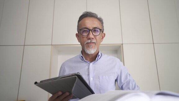 亚洲华人资深男教授家教老师听他的成人学生使用笔记本电脑在家里工作