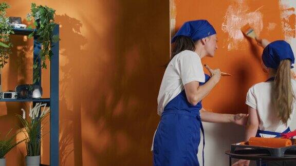 妈妈和孩子玩橙色的油漆和装修房子