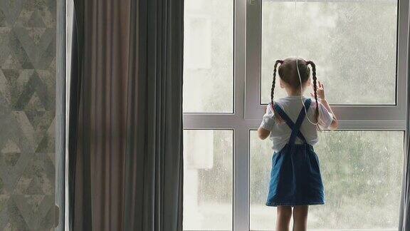 小女孩站在窗前凝视着