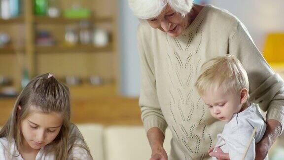 慈爱的奶奶帮助孙女做作业拥抱宝宝