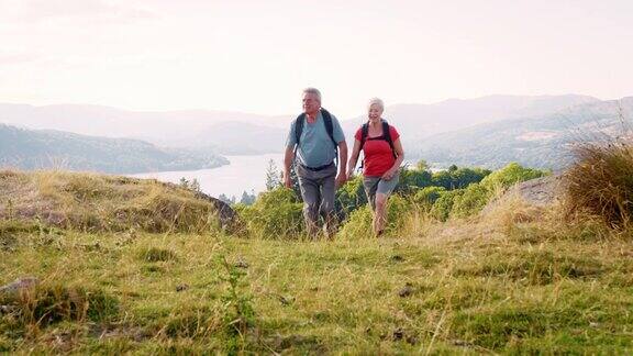 一对老年夫妇一起爬山穿越英国湖区乡村的慢镜头