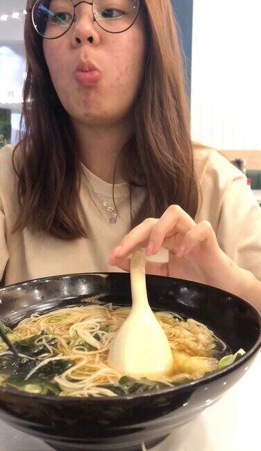 年轻的亚洲女子用筷子吃乌冬日本面条汤智能手机垂直视频
