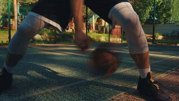 夏季男子篮球运动员在室外场地练习控球、胯下运球