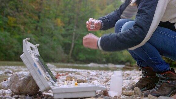 白人女性生物学家从河里取水样做pH值测试